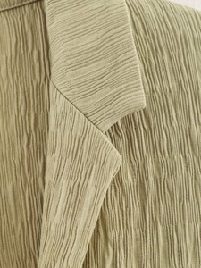 Détail de l'ensemble blazer olive clair montrant le tissu gaufré et les finitions du col