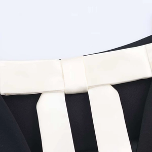Detail of black fabric with a contrasting white satin bow and smooth silk texture