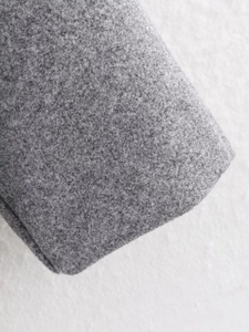 Macro shot of grey wool fabric texture and stitching detail on the winter overcoat