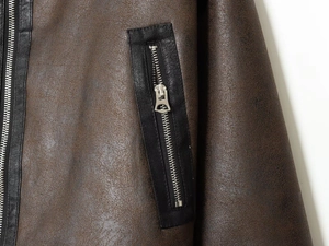 Detail view of distressed brown leather texture with black piping and silver zipper