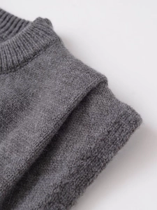 Detail of dark grey knit vest showing pleated shoulder and premium ribbed fabric texture