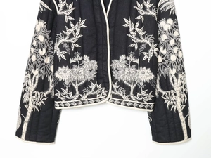 Close-up of quilted jacket with white floral embroidery and contrast piping details