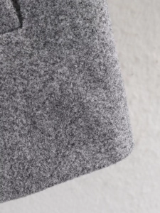 Macro shot showing the thick melange grey wool-like fabric texture of the winter coat