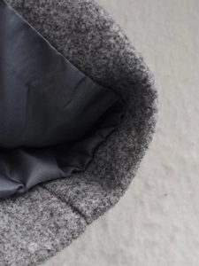 Close-up of grey wool blend coat texture showing premium stitching and silk-like inner lining