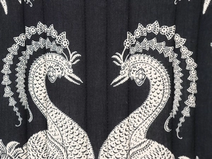 Detail of black quilted fabric featuring white symmetrical swan embroidery and stitching