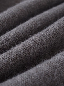 Macro shot of dark taupe knitted fabric texture showing pleated soft fiber details
