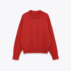 Close-up detail of red crewneck sweater showing ribbed cuffs and soft knit texture