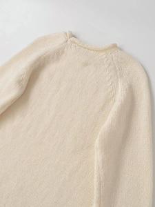 Close-up of cream chunky knit sweater showing the round neck and soft wool texture
