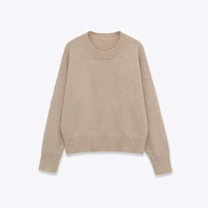 Detailed close-up of ribbed cuffs and hem on a soft beige crew neck sweater