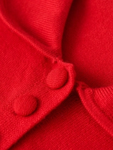 Detail showing the red knitted fabric texture and matching fabric-wrapped buttons on cardigan