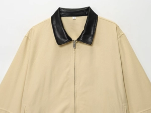 Detail of khaki jacket with black leather collar, silver metal zipper, and white size tag