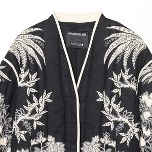 Quilted jacket with white tropical plant embroidery on black fabric and contrast piping