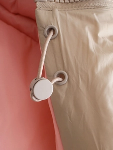 Detailopname van het trekkoord en de rits op het roze met beige warme vest