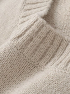 Close-up of soft beige knit fabric texture showing high-quality wool fibers and stitch detail