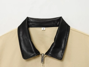 Close-up of khaki jacket featuring a black faux leather collar and silver metal zipper