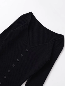 Close-up of black ribbed knit midi dress featuring a V-neck and decorative front buttons