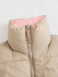 Detail van winddichte opstaande kraag en roze contrastvoering op beige vest