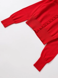 Detailed close-up of vibrant red knit cardigan with fabric-covered buttons and ribbed cuffs