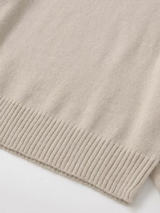 Macro shot of minimalist oatmeal knitted sweater detail with ribbed hem and fine texture