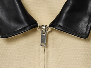 Detail of black leather collar contrast and silver metal zipper on khaki canvas jacket