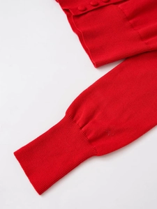 Detail of red knitted cardigan featuring ribbed cuffs and matching round fabric buttons