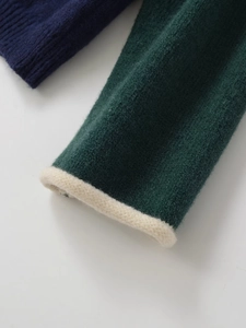 Close-up of contrast knit sleeve with deep green and navy tones and soft ribbed texture