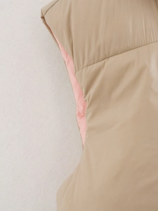 Detailopname van kaki gewatteerd vest met roze voering en nauwkeurige stikseldetails
