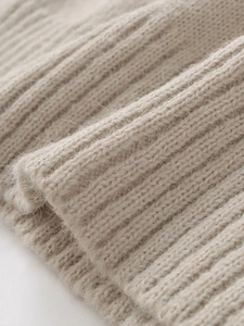 Close-up of soft oatmeal knit fabric with ribbed texture and warm fuzzy fiber details