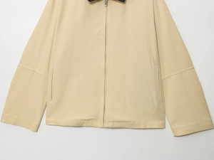 Detailed view of beige canvas jacket featuring metal zipper and vertical side pockets