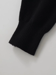 Nahaufnahme des feingestrickten schwarzen Ärmels mit geripptem Bündchen am Pullover