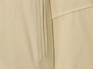 Detailed close-up of double-stitched seams on high-quality khaki canvas jacket fabric