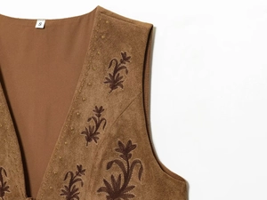 Detail of floral embroidery on brown suede vest with white size S neck label