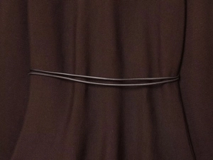 Close-up of the knitted brown dress with a waist belt highlighting texture and fit