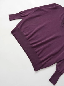 Detail of the V-neckline and textured knit fabric on a deep purple relaxed sweater