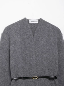 Détail du cardigan gris à col en V avec texture duveteuse et ceinture en cuir noir