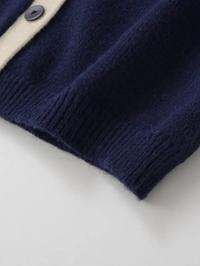 Detailed close-up of navy knit cardigan with cream trim and black resin button