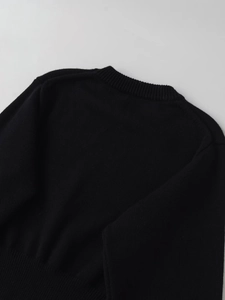 Detailansicht eines schwarzen Rundhals-Strickpullovers mit Rippbündchen und Ausschnitttextur