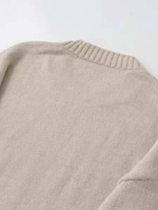 Detailed close-up of ribbed crewneck and soft knit texture on beige pullover sweater