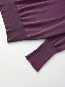 Detailed macro view of the ribbed cuffs and hem on this dark purple knitted sweater