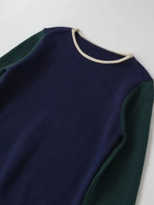 Detail of color-block knit sweater with navy body, green sleeves and cream collar trim