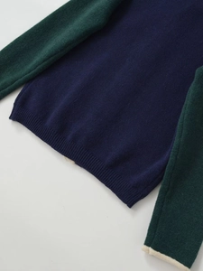 Close-up of contrast knit sweater featuring navy body and green sleeves with ribbed cuffs