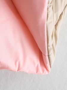 Detail van beige gewatteerde bodywarmer met roze voering en glanzende afwerking