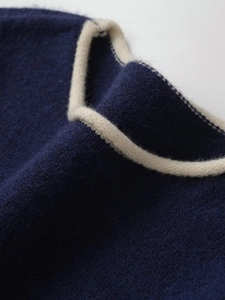 Detail of navy blue knit sweater featuring premium cream contrast trim on the neckline