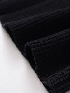 Macro detail of high-quality black ribbed knit fabric showing texture and elasticity