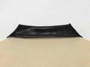 Close-up of beige canvas jacket featuring a contrasting black leather collar detail
