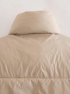 Detailopname van de opstaande kraag en het stiksel op de beige gewatteerde bodywarmer