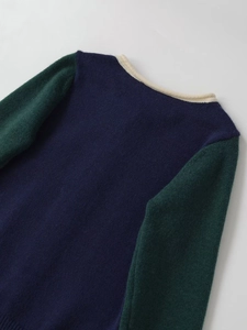 Detail view of contrast knit cardigan showing navy body and green sleeve textures