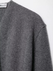 Gros plan sur la texture du pull en maille gris foncé avec étiquette de marque et taille