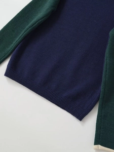 Detail of color-block knit sweater with navy body, green sleeves and cream cuffs