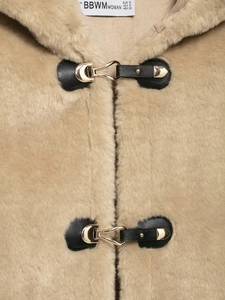Dettaglio del gilet in pile beige con fibbia in metallo, cinturino in pelle e texture morbida